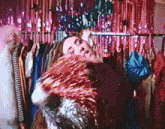 a woman is laying in front of a rack of clothes and holding a piece of tinsel