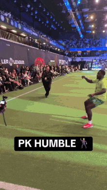 a man in a green shirt is running on a soccer field with a sign that says pk humble on it