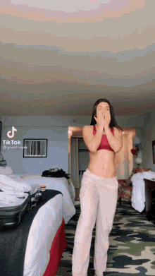 a woman in a red top and pink pants is standing in a hotel room .
