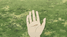 a hand is holding a blue object in front of a grassy field
