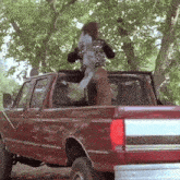 a man is standing in the back of a red pickup truck