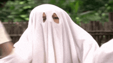 a person is dressed as a ghost with a white sheet covering their face .