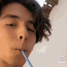 a young man is drinking through a straw and looking at the camera .