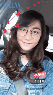 a woman wearing glasses and a denim jacket is smiling with hollaa written in the background
