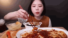 a woman is eating food with chopsticks and a bowl of soup