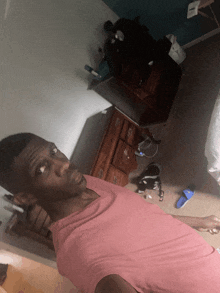 a man in a pink shirt is taking a picture of himself