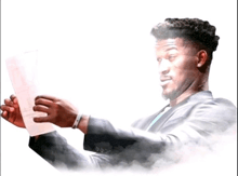 a man in a suit is holding a piece of paper in his hand