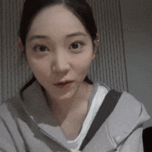 a close up of a woman wearing a gray hoodie