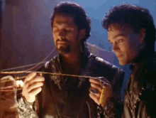 two men in leather jackets are holding a rope in their hands