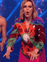 a woman wearing a colorful jacket is dancing on stage