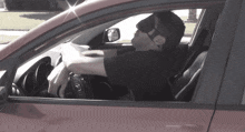 a man wearing a blindfold is driving a red car