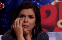 a woman with red nails and a ring on her finger is crying .