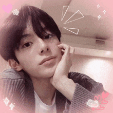 a young man with his hand on his chin and a pink background