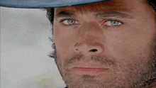 a man with a beard is wearing a hat and looking at the camera