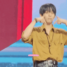a man in a yellow shirt is making a peace sign with his fingers