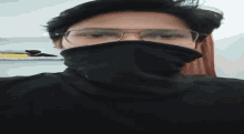 a person wearing glasses and a black sweater covering their mouth