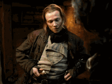 a man with long blonde hair is wearing a brown jacket