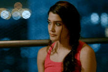 a woman in a red tank top stands in front of a blue background