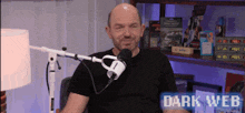 a man in a black shirt is sitting in front of a microphone with the words dark web on the bottom right