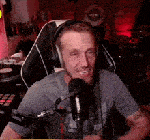 a man wearing headphones and a microphone is sitting in a chair in front of a microphone .