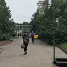 a woman walking down a street holding a basketball