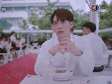 a man in a white shirt is sitting at a table eating food .