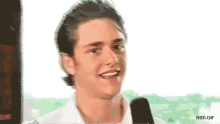 a man is smiling in front of a microphone with rbd.gif below him
