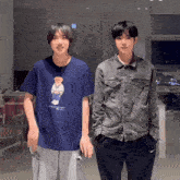 two young men standing next to each other one wearing a blue polo bear t-shirt