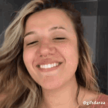 a woman with a nose ring smiles with her eyes closed .