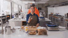 a woman in an apron is standing in a kitchen holding a jar of mayonnaise