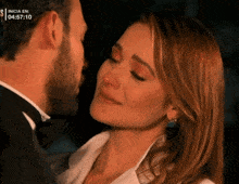 a man in a tuxedo kissing a woman with the time 04:57:10 on the bottom