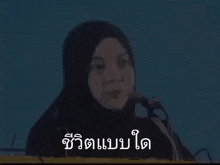 a woman wearing a hijab is talking into a microphone .