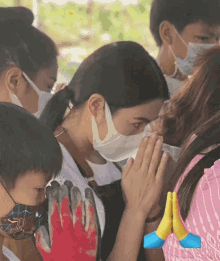 a woman wearing a mask is praying with her hands together