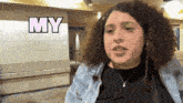 a woman with curly hair is standing in front of a wall that says my