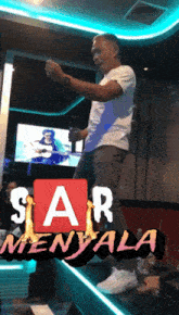 a man in a white shirt stands in front of a sign that says star menyala