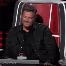 a man is sitting in a chair with a nbc logo on the bottom