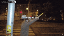 a man is holding a baton in front of a pole that says arogantnia cz
