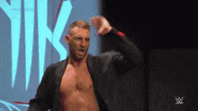 a man without a shirt is standing in front of a sign that says w