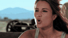 a woman in a tank top is making a funny face with her mouth open