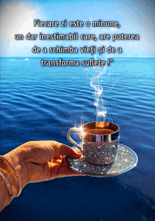 a person is holding a cup of coffee in front of a blue ocean