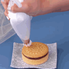 a person is frosting a cookie on a white plate