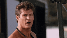 a man without a shirt is wearing a necklace and making a funny face