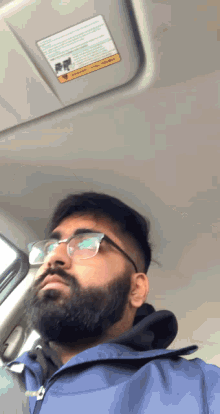 a man with glasses and a beard is sitting in a car