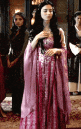 a woman in a pink dress is standing in front of a group of women
