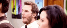 a man with a beard is talking to a woman while standing next to each other .
