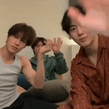 a group of young men are sitting on a bed waving