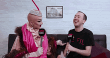 a man wearing a shirt that says fil is sitting next to a woman in a pink dress