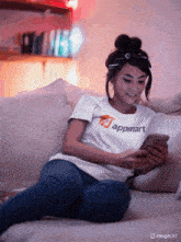a woman wearing a t-shirt that says appmart is sitting on a couch