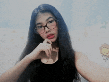 a girl wearing glasses and a black tank top is taking a selfie
