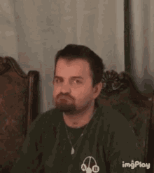 a man with a beard is making a funny face with his eyes closed .